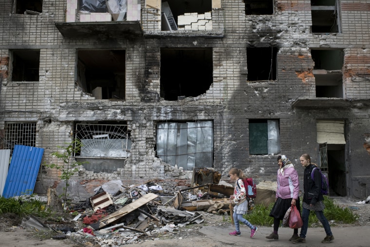 A family passes by a residential building in Kharkiv, Ukraine, that was hit by multiple Russian strikes Thursday.