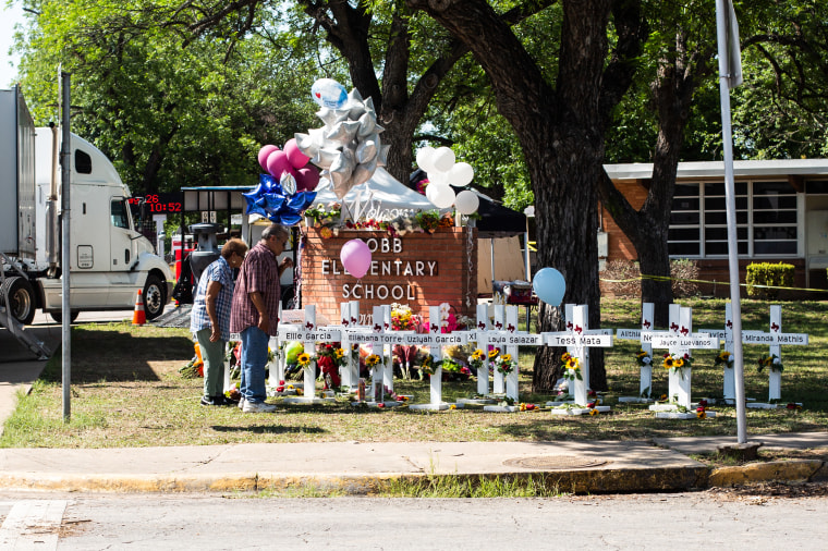 People stand looking at a memorial at Robb Elementary School following a mass shooting on May 26, 2022 in Uvalde, Texas.