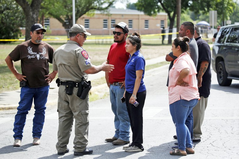 A policeman talks to people asking for information outside of the Robb Elementary School