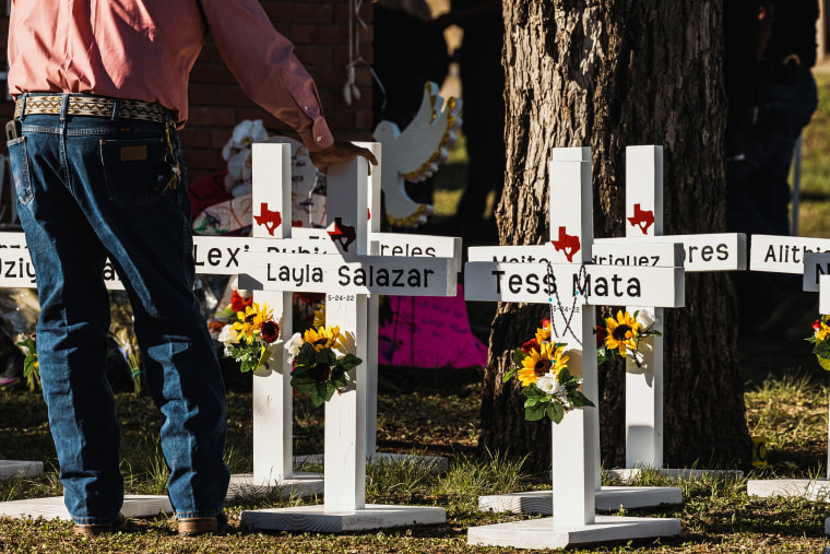 Image: A man places his hand on a cross bearing the names of the victims of a mass shooting in front of Robb Elementary School on May 26, 2022 in Uvalde, Texas.