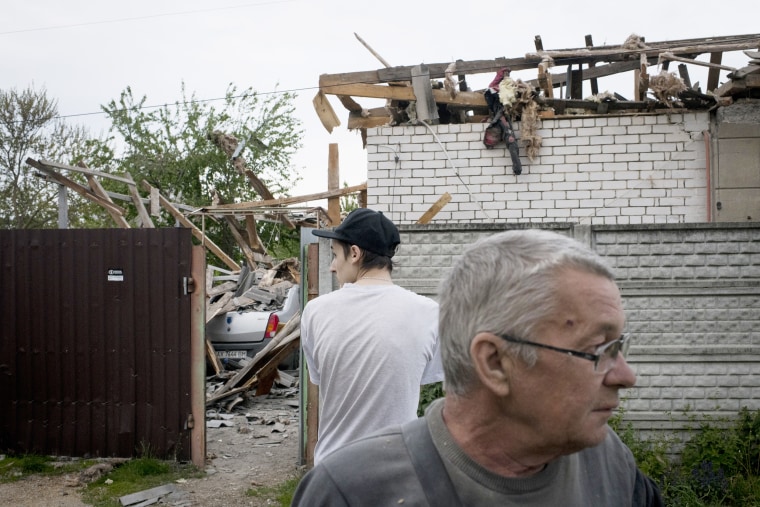 Image: Yurii Kuzinskiy, right, stands in the street in front of his destroyed home in the Sortirovka neighborhood of Kharkiv, Ukraine on May 20, 2022.