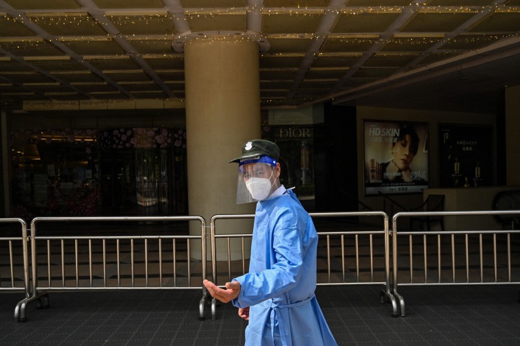 A security guard stands outside the entrance of a closed shopping mall