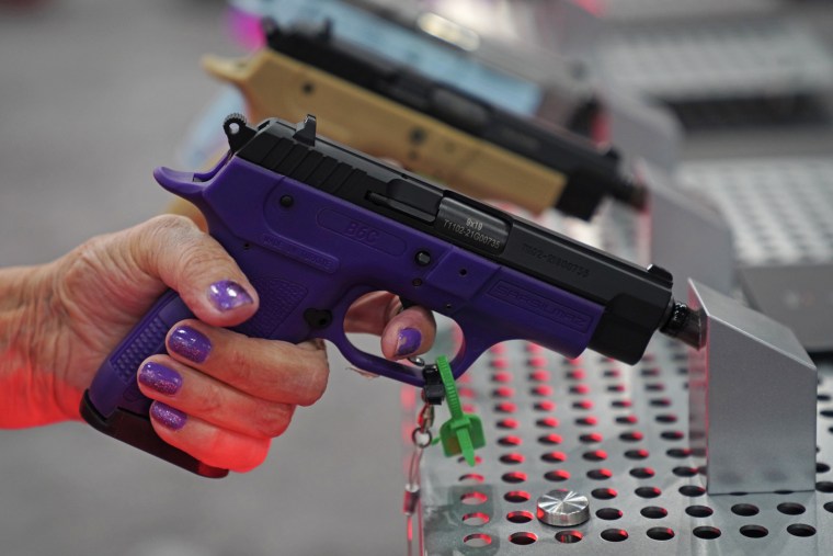 A woman grips a pistol at the annual meeting Friday. 