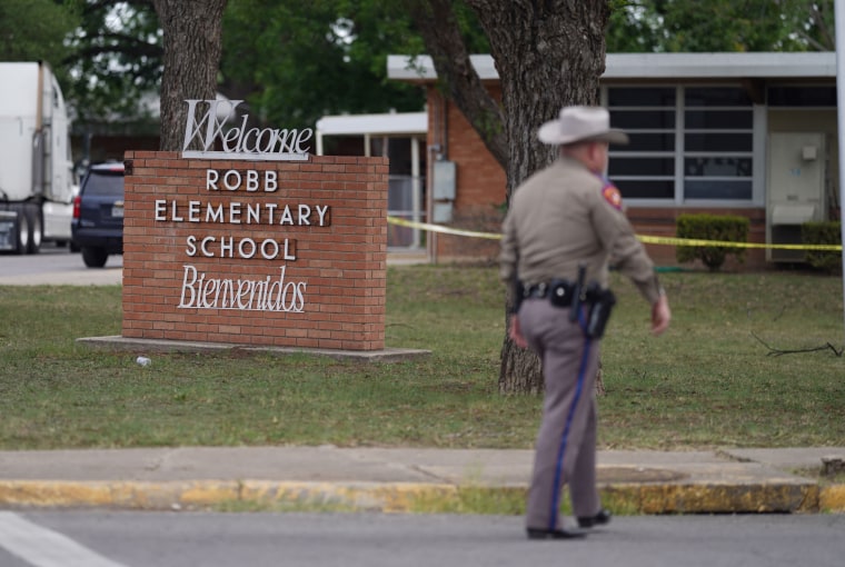 An officer walks outside of Robb Elementary School