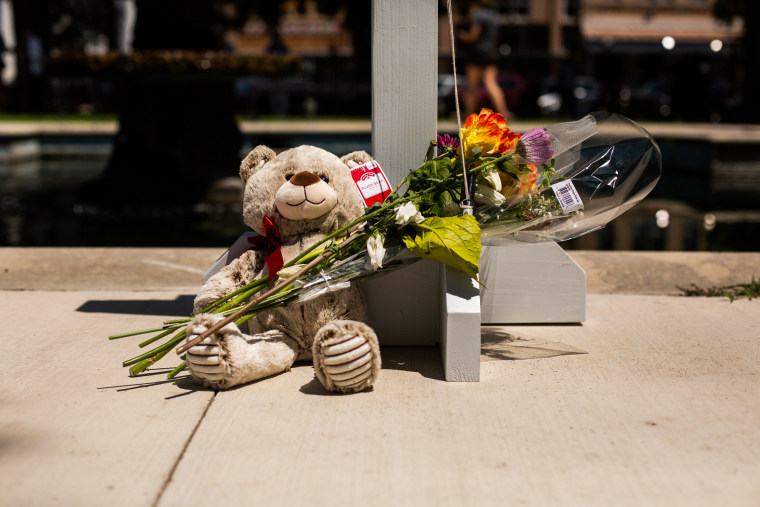 A teddy bear with a bouquet of flowers leans against a cross commemorating a victim of the school massacre in Uvalde, Texas, on May 26, 2022.