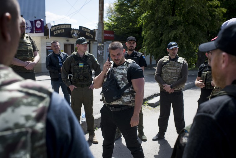 Image: Alexander Ilyenkov briefs members of his team in a parking lot before heading to canvas crime scenes in Mala Rohan on May 24, 2022 in Kharkiv, Ukraine.