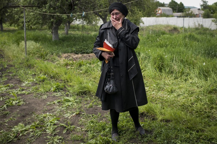 Olga Kotenko waits as investigators exhume the remains of her son last week in Vilhivka.