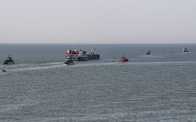 A Russian vessel, center, escorted by Russian military boats, departs from the port in Mariupol, Ukraine, on May 31, 2022.