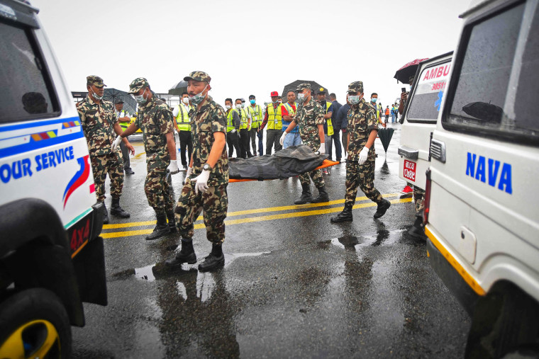 Image: Members of Nepals security personnel carry the body of a victim of Twin Otter aircraft, operated by Tara Air that crashed earlier in the Himalayas, at the airport in Kathmandu on May 31, 2022.