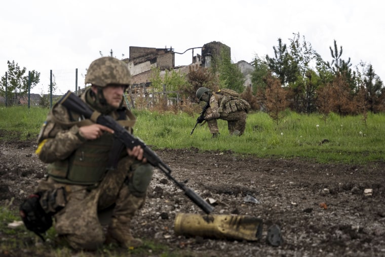 Ukrainian soldiers squat during a patrol