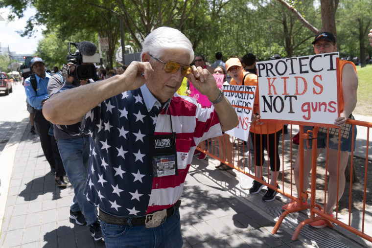 Un miembro de la Asociación Nacional del Rifle se tapa los oídos con los dedos mientras pasa junto a los manifestantes durante la reunión anual de la NRA en el Centro de Convenciones George R. Brown en Houston.