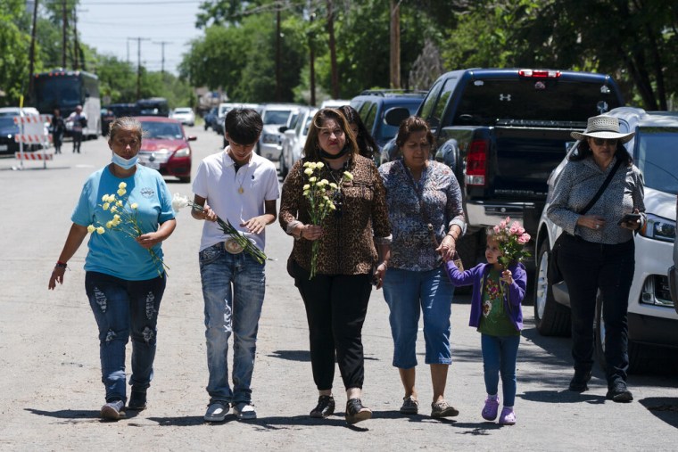 Un grupo de personas camina hacia una ceremonia en honor a las víctimas del tiroteo del martes en la Escuela Primaria Robb en Uvalde, Texas, el miércoles 25 de mayo de 2022.