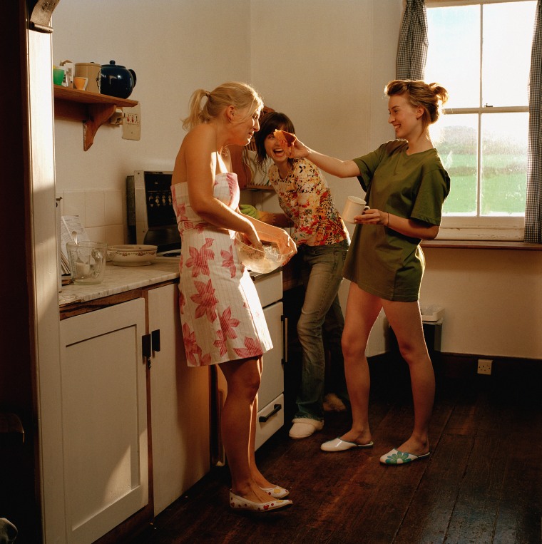 Three young women in kitchen, laughing