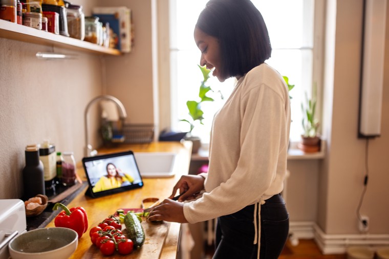 Woman video calling friend while cooking at home