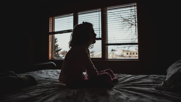 Silhouette of Little girl sitting on bed