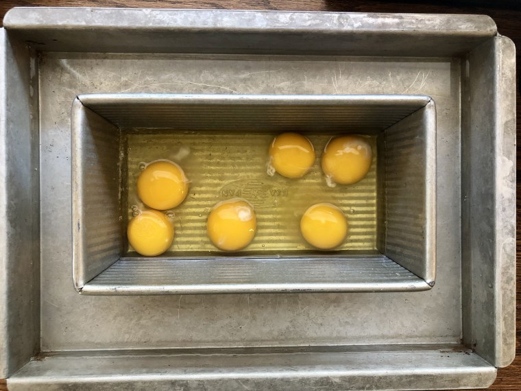 Cracked eggs in a water bath are ready for baking.
