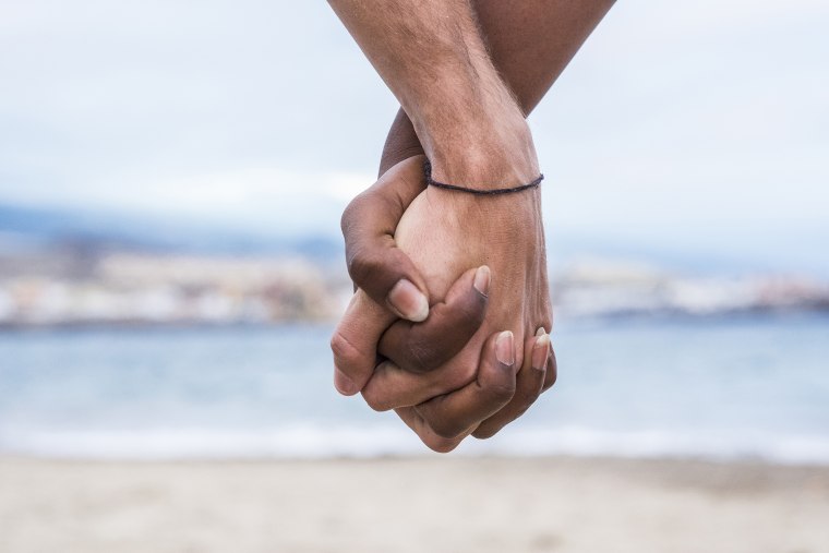 Close-up of two hands connected on the beach