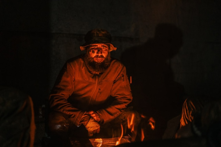 A Ukrainian soldier sits near a fire at the Azovstal steel plant to stay warm.