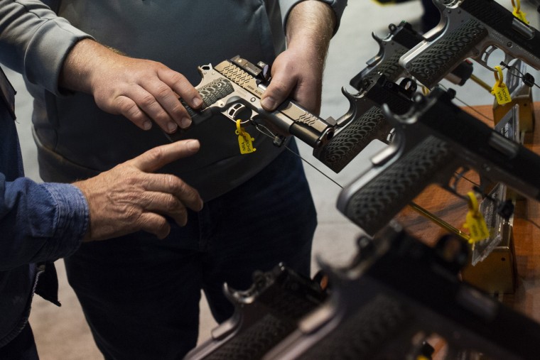 NRA members are seen examining handguns and other