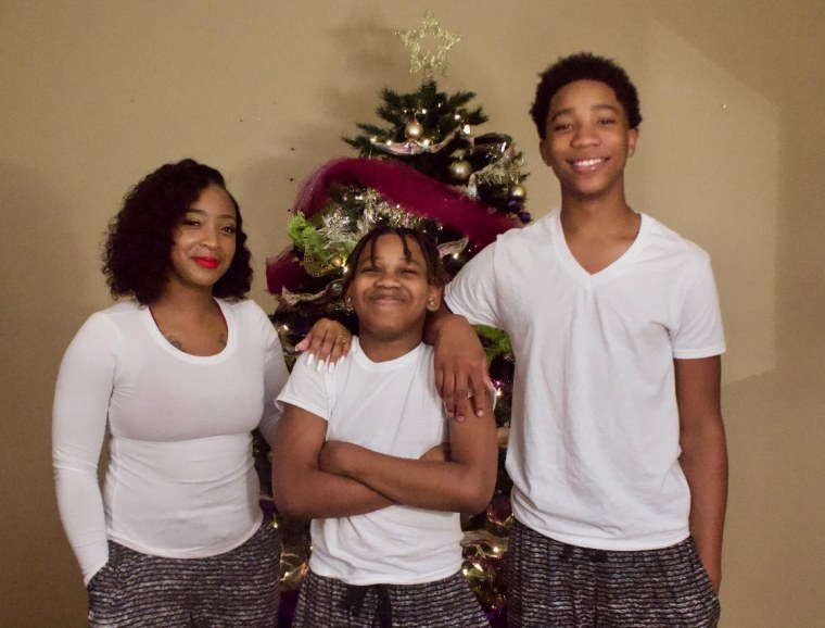 Adrian McDougles, center, with his mother Kyneshia and older brother Onterrio in December 2020.