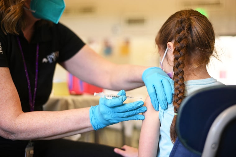 A nurse administers the Covid-19 vaccine to a girl