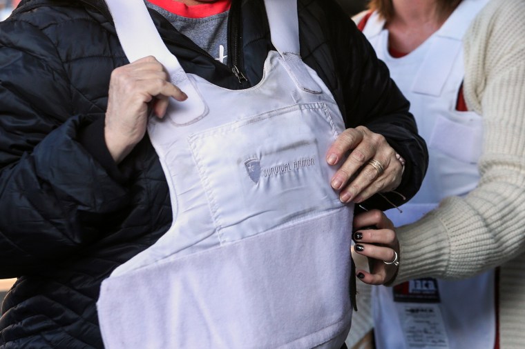 A teacher puts on a bulletproof vest during a live fire training session in Thistle, Utah, on Saturday, Oct. 5, 2019.