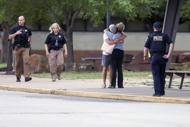 Two people hug outside at Memorial High School, where people were evacuated from the scene of a shooting at the Natalie Medical Building in Tulsa, Okla., on Wednesday.