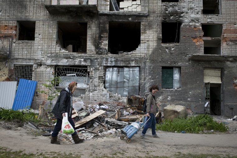 Image: Two women pass by a residential building at the site of multiple Russian strikes on May 25, 2022 in Kharkiv, Ukraine.