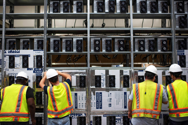 Workers install a new row of Bitcoin mining machines