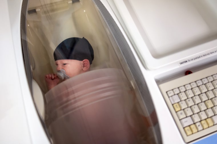 Researchers calculated the body fat percentage of two-week-old Jameson Hardy in a machine called a pea pod.  Jameson's mother, Julie Hardy, works in the lab, and volunteers to show Jameson how the measurements are taken.