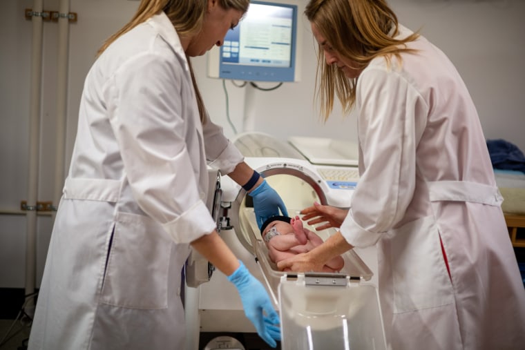 Redman, right, and Ph.D. Emily Flanagan, place baby Jameson Hardee in the Pea Pod.