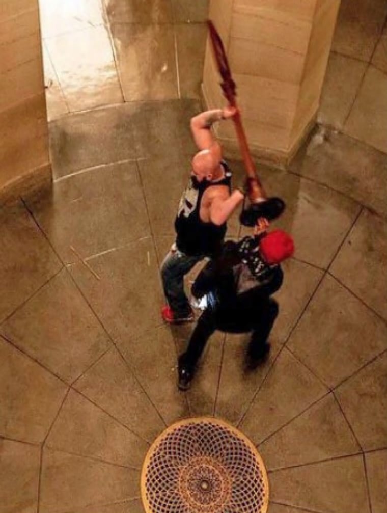 Joshua Pruitt picks up a “Quiet Please” sign and throws it across an atrium at the Capitol on Jan. 6, 2021.