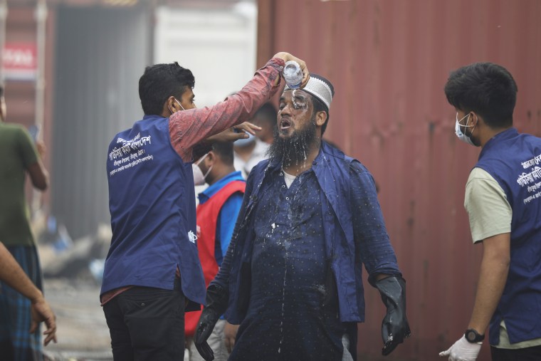 A man pours water on the face of a rescue worker amid continued efforts to contain the blaze in Chittagong, Bangladesh.