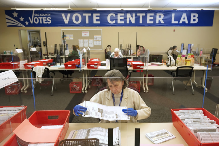 Election worker Donna Young inspects a mail-in ballot for damage at the Sacramento County Registrar of Voters in Sacramento, Calif., on June 3, 2022.