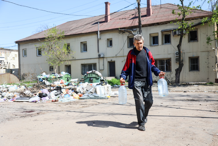 A local resident carries water bottles in Mariupol under the control of Russian military and pro-Russian separatists on April 29, 2022.
