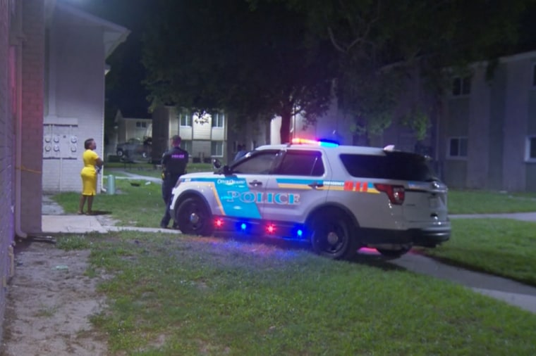 A police officer speaks with an unknown person at the apartment complex where the shooting occurred.