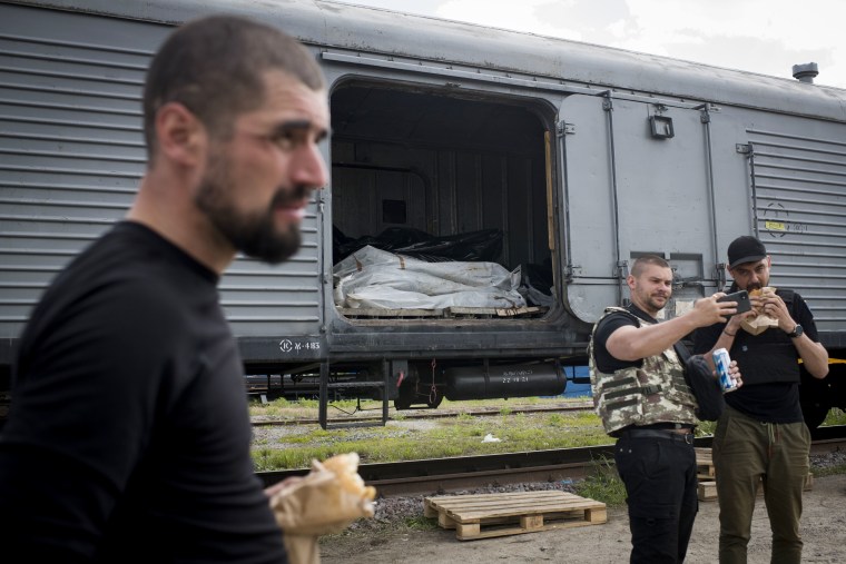 A Kharkiv prosecutor takes a selfie in front of a refrigerated train used to store the remains of Russian soldiers in Kharkiv.