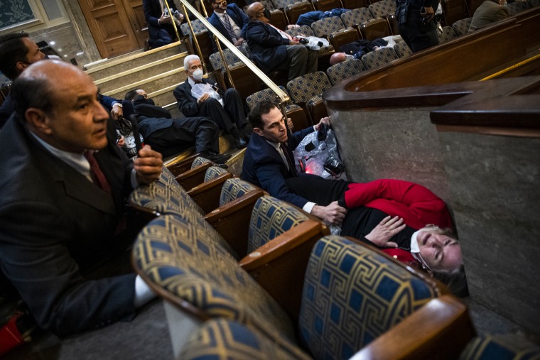 Rep. Jason Crow, D-Colo.,  comforts Rep. Susan Wild, D-Pa., while taking cover as Trump supporters disrupt the joint session of Congress to certify the Electoral College vote on Jan. 6, 2021.