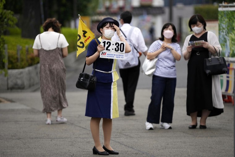 A tour guide holds a banner showing an assembly time for her group on June 10, 2022, in Tokyo.