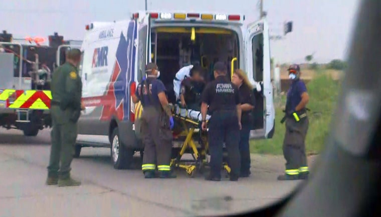 A young migrant woman is taken into an ambulance after suffering an apparent injury to her leg after falling from a nearby border wall in Sundland Park, N.M. 