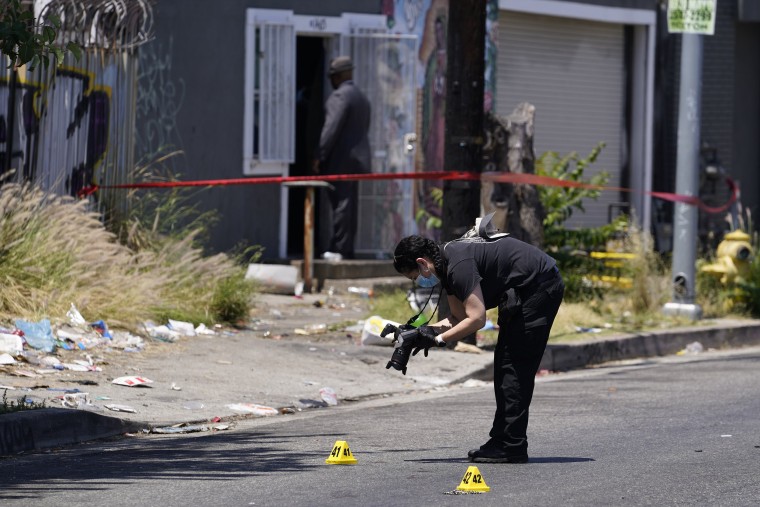 Image: A field forensic photographer documents evidence after a shooting at a warehouse party in Los Angeles on June 12, 2022.