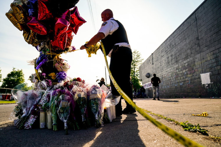 A police officer removes tape from scene of the mass shooting at a Tops Friendly Markets location in Buffalo, N.Y., on May 19, 2022.