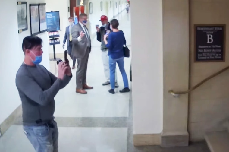 Video showing the same man taking photos of hallways and staircases on the tour led by Loudermilk.