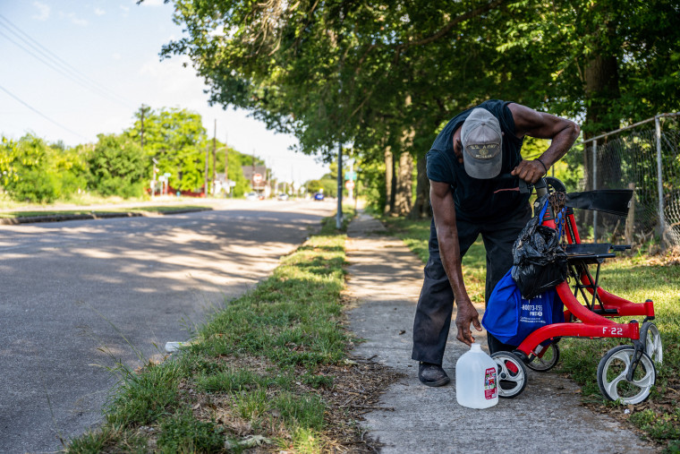 U.S. Veteran Bennie Earsle, 72, takes a break on a sidewalk after buying a jug of water on June 10, 2022, in Houston.