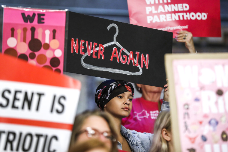August Mulvihill, of Norwalk, Iowa, center, holds a sign during a rally to protest recent abortion bans, on May 21, 2019, at the Statehouse in Des Moines, Iowa.
