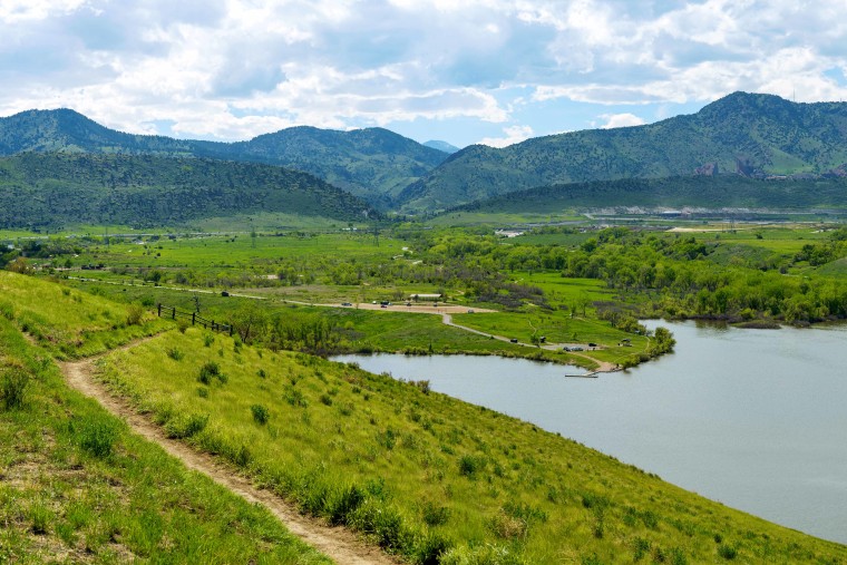 Bear Creek Lake - A panoramic Spring view of a biking trail winding at side of Mt. Carbon, overlooking Bear Creek Lake, with Mt. Morrison rising high at background. Bear Creek Lake Park, Denver-Lakewood, Colorado, USA.