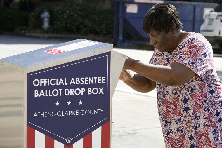 A voter drops a ballot off during early voting in Athens, Ga., on Oct. 19, 2020.