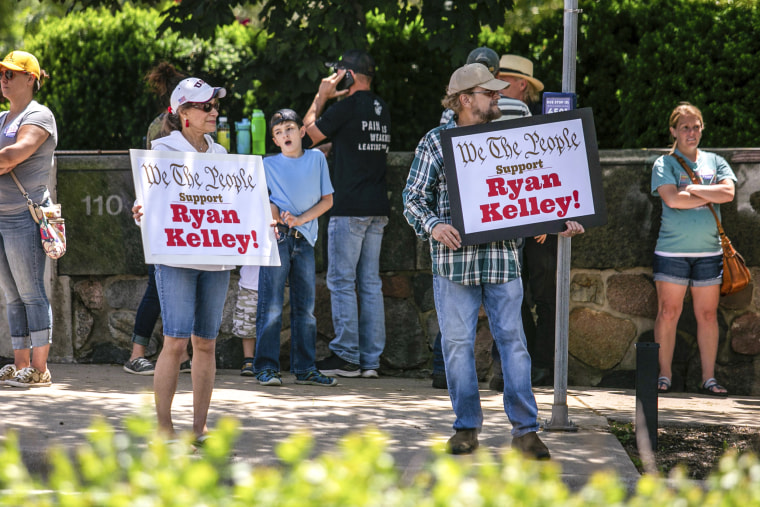 Image: Supporters of Michigan gubernatorial candidate Ryan Kelly hold up signs as traffic passes by on Michigan Street while waiting for him to come out of the U.S. District Court in Grand Rapids, Mich., on June 9, 2022.