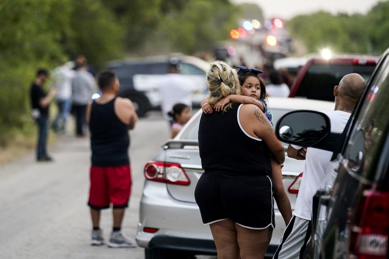 Image: Onlookers stand near the scene where a tractor trailer with multiple dead bodies was discovered, on June 27, 2022, in San Antonio.