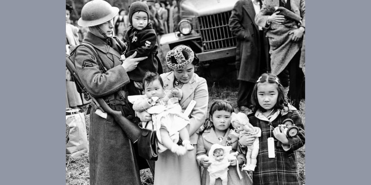 Image: Cpl. George Bushy, left, a member of the military guard  holds the youngest child of Shigeko Kitamoto, center,  on March 30, 1942 as she and her children are evacuated from Bainbridge Island, Wash.
